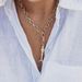 Gold chain necklace with a pendant worn by a person in a light blue shirt.