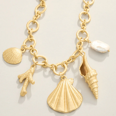 Gold necklace with shell and starfish charms on a light background