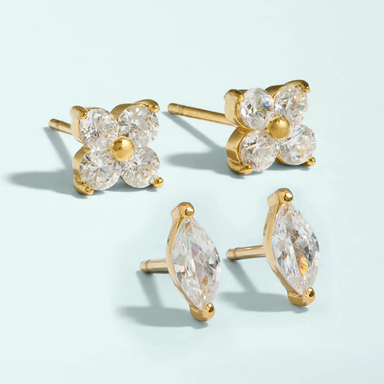 Gold and clear crystal stud earrings on a light blue background